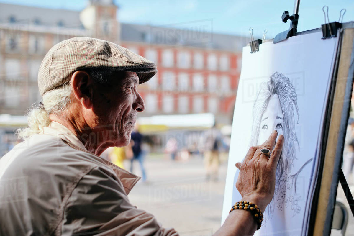 Mature male street artist drawing on canvas in town square, head and shoulders, Madrid, Spain Royalty-free stock photo