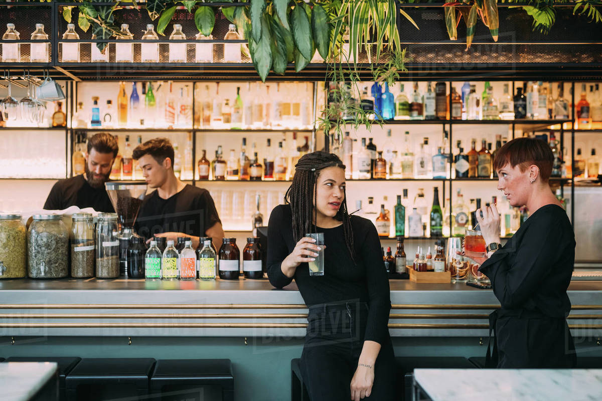 Portrait of two young women sitting at a bar counter and two young men