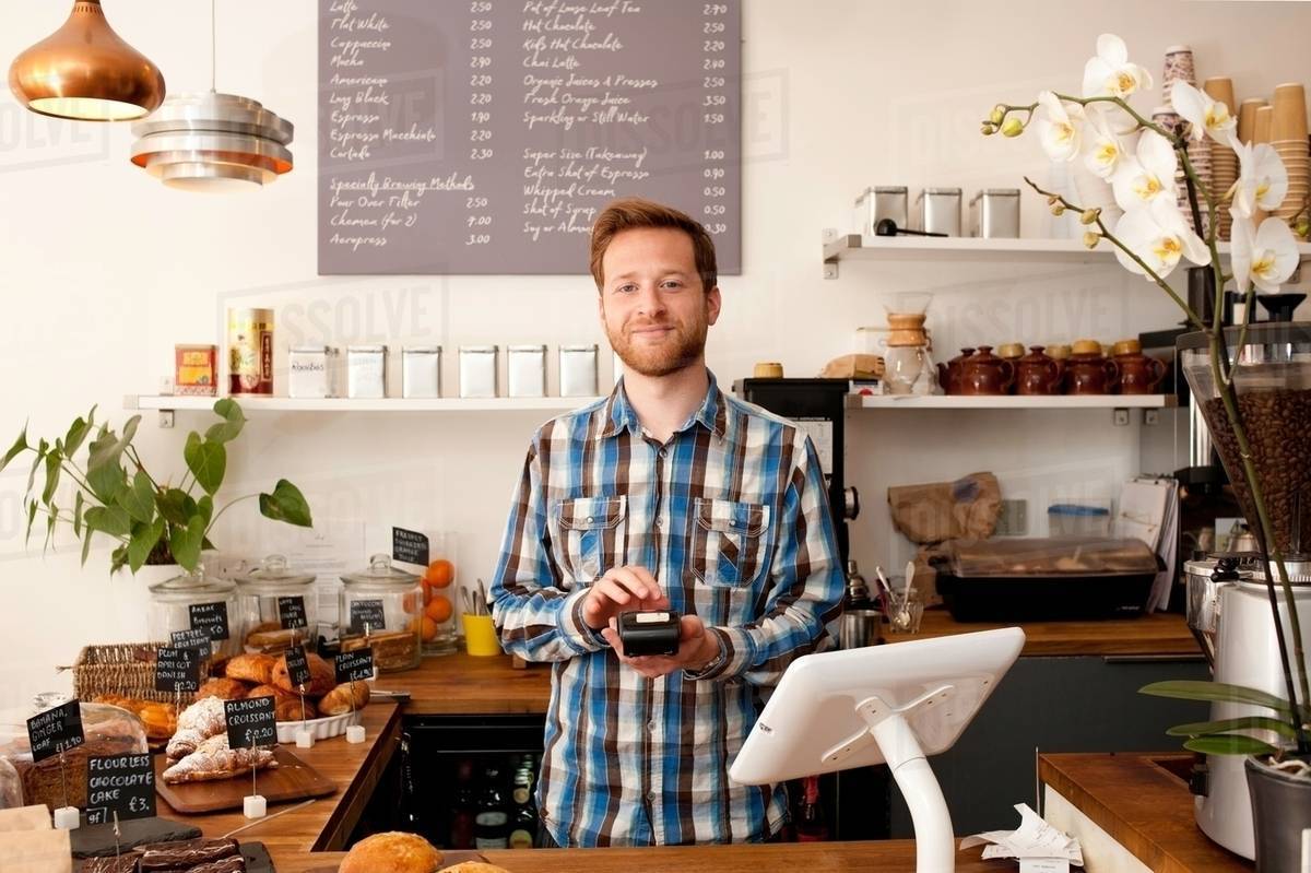 Portrait of cafe waiter with card machine behind counter - Stock Photo -  Dissolve