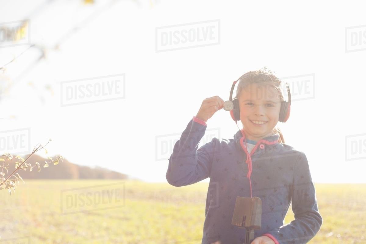 Portrait of girl metal detecting in field holding up silver coin Stock Photo Dissolve