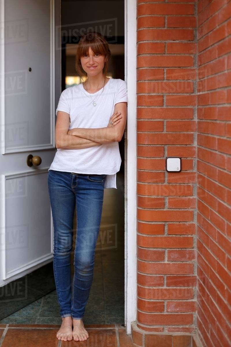 Full length view of mid adult woman leaning against door frame, arms
