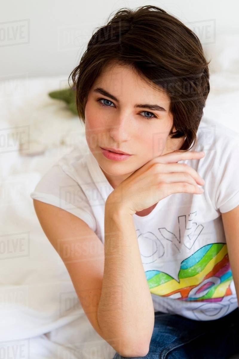 Woman resting chin in hand on couch Stock Photo Dissolve