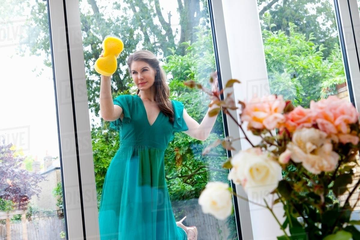 Young woman cleaning patio door Stock Photo Dissolve