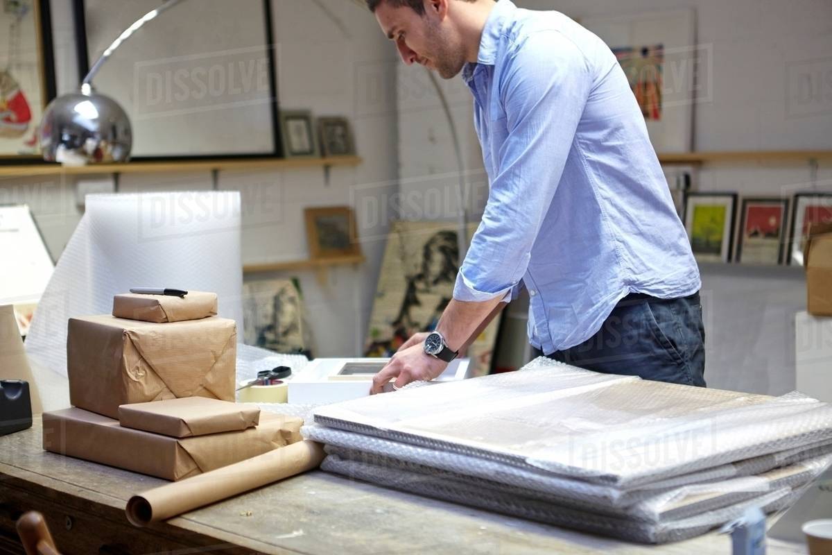 Man Wrapping Frames In Bubble Wrap On Table Picture Framers Man Wrapping Frames In Bubble Wrap On Table Picture Framers Work