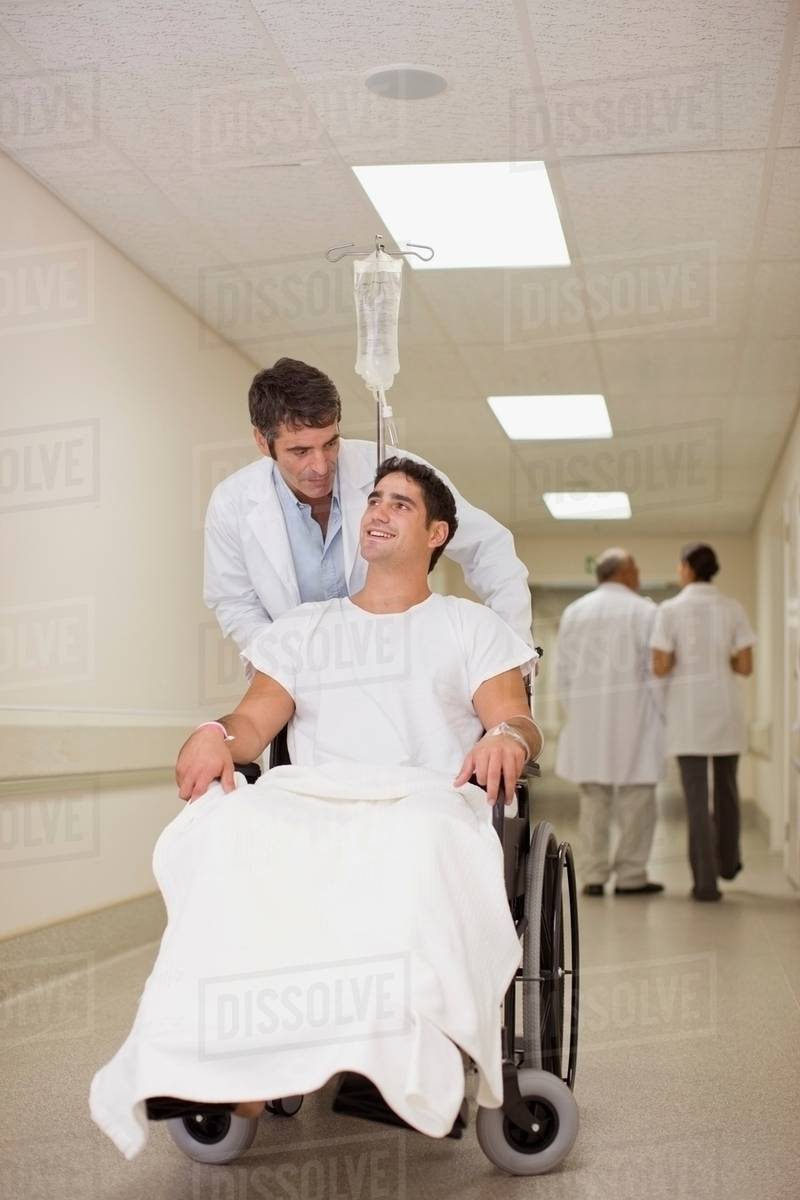 Doctor pushing patient in wheelchair Stock Photo Dissolve