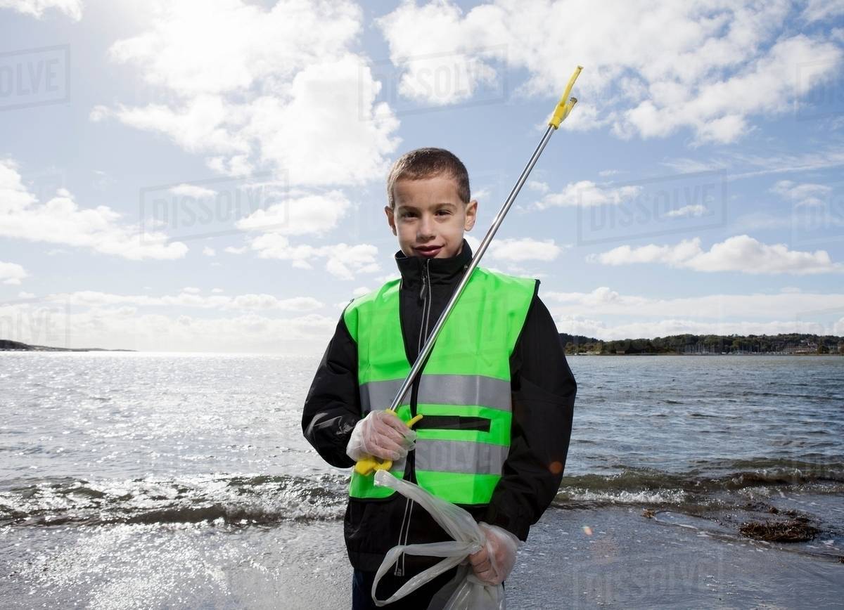 Boy in safety vest cleaning beach Stock Photo Dissolve