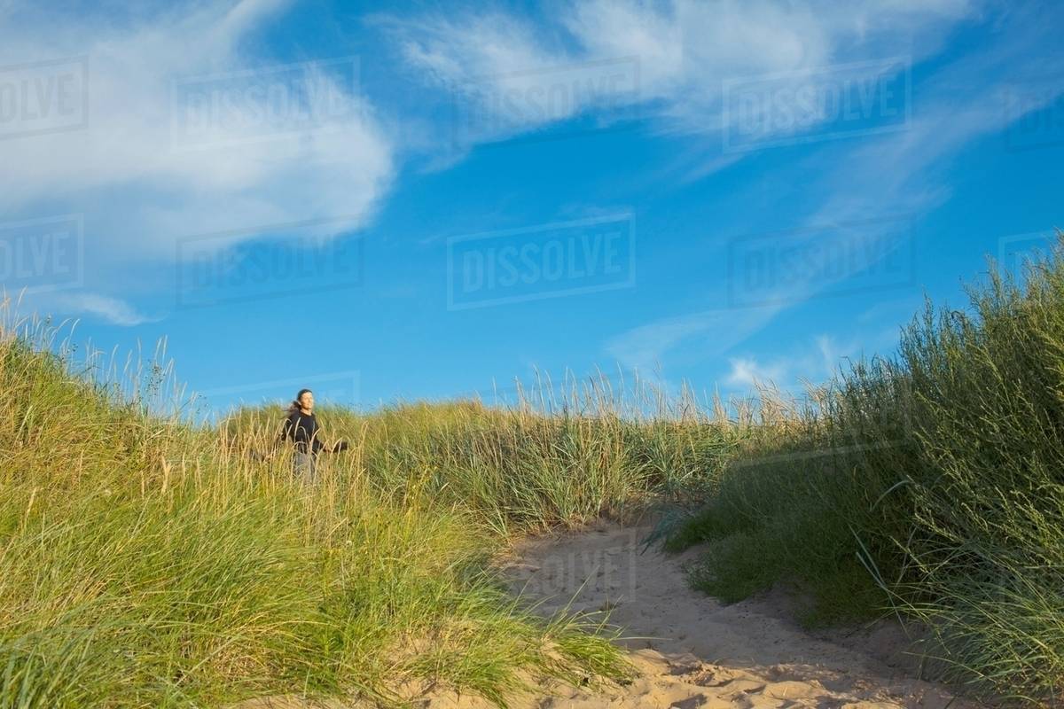 Woman walking in long grass Stock Photo Dissolve