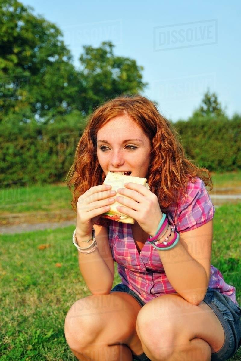 Teenage girl eating sandwich in backyard Stock Photo Dissolve