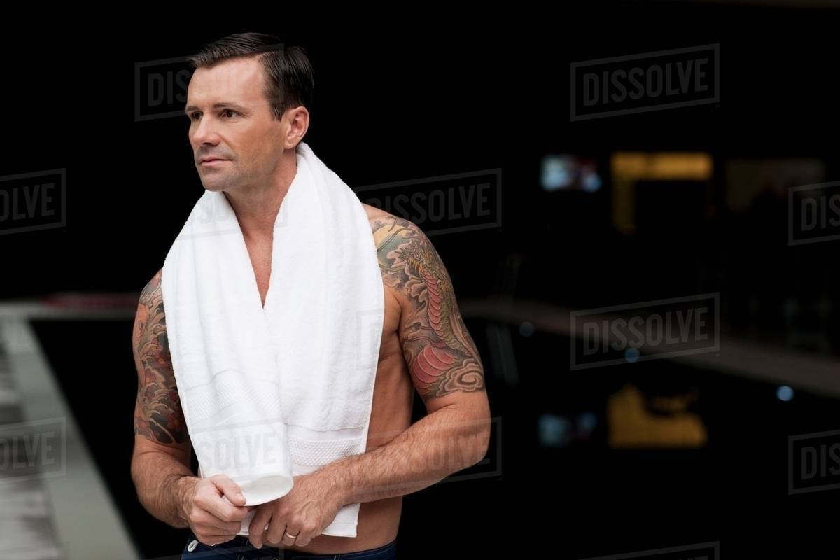 Man wearing towel by pool at night Stock Photo Dissolve