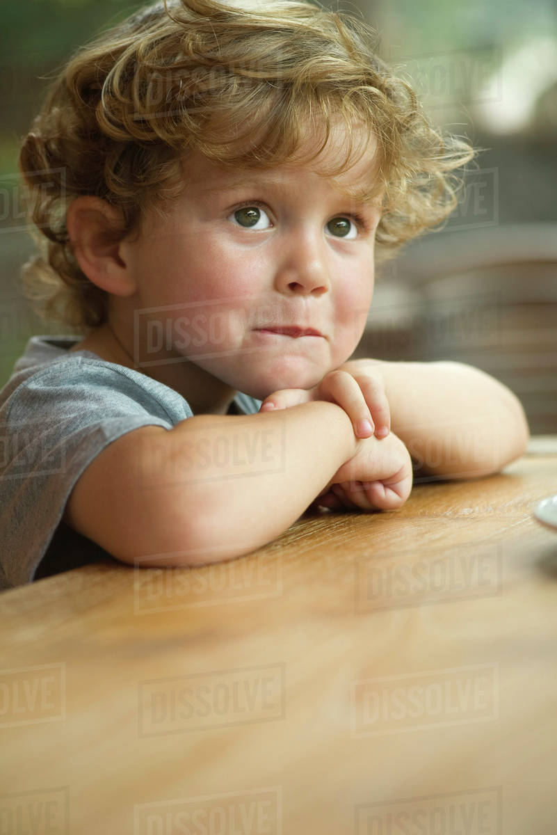 Little boy resting chin on arms, looking away in thought, portrait