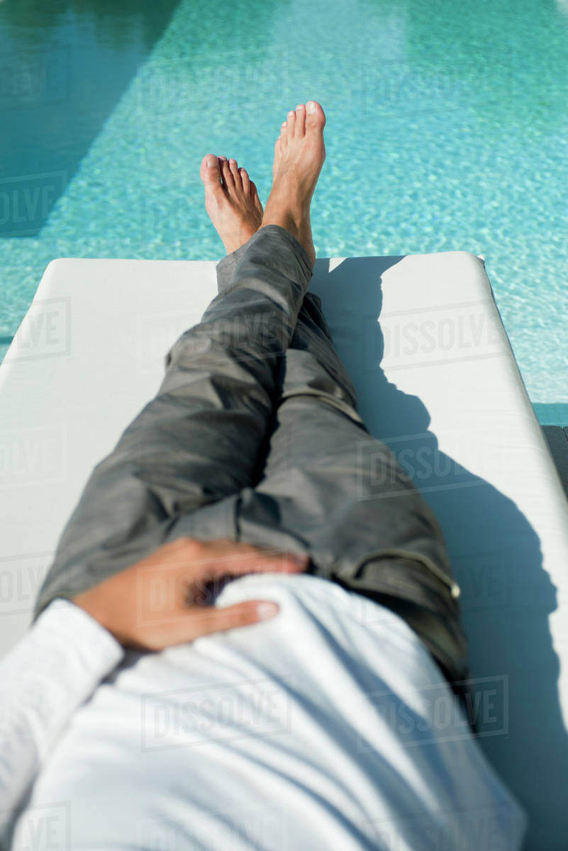 poolside lounge chairs on Man Relaxing On Lounge Chair Beside Pool Stock Photo Dissolve