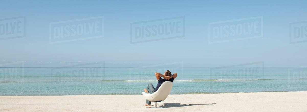 Man Relaxing In Chair On Beach Rear View Stock Photo Dissolve Man Relaxing In Chair On Beach Rear View