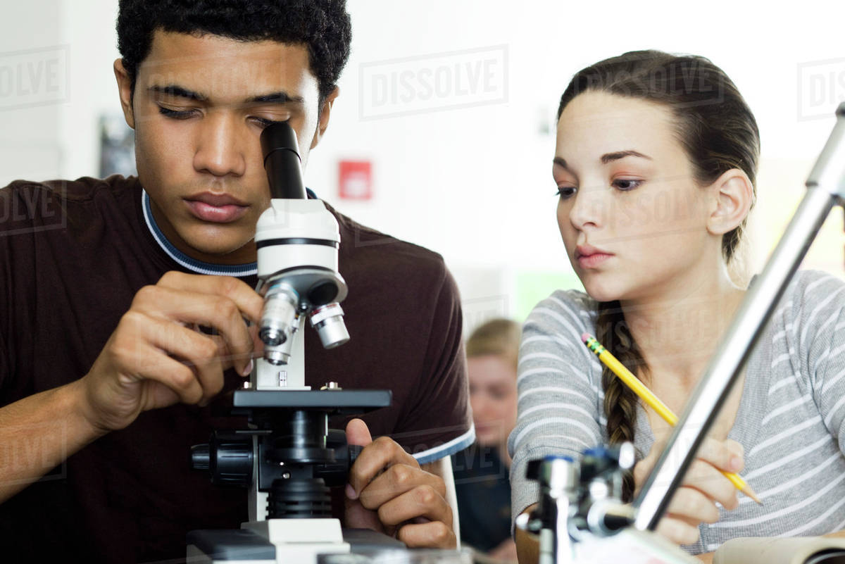 Student looking through microscope in science class Stock Photo