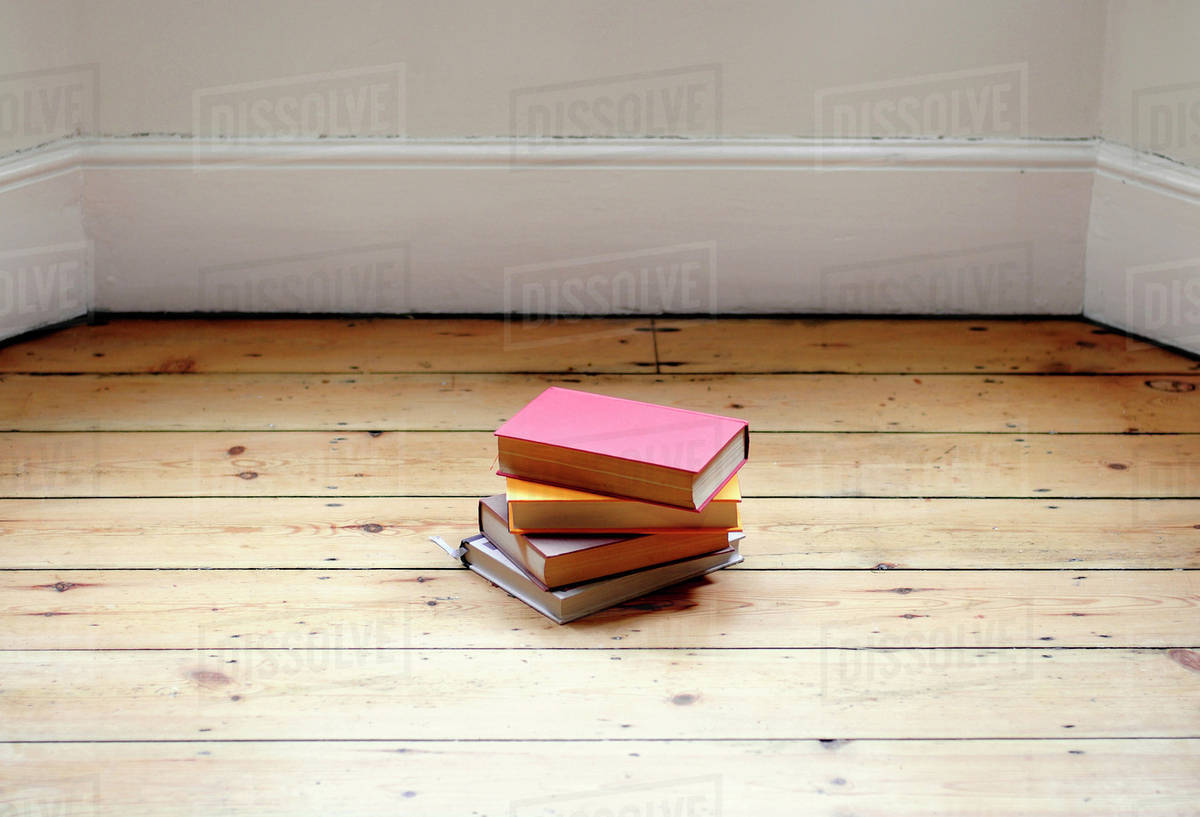 Books stacked on hardwood floor Stock Photo Dissolve
