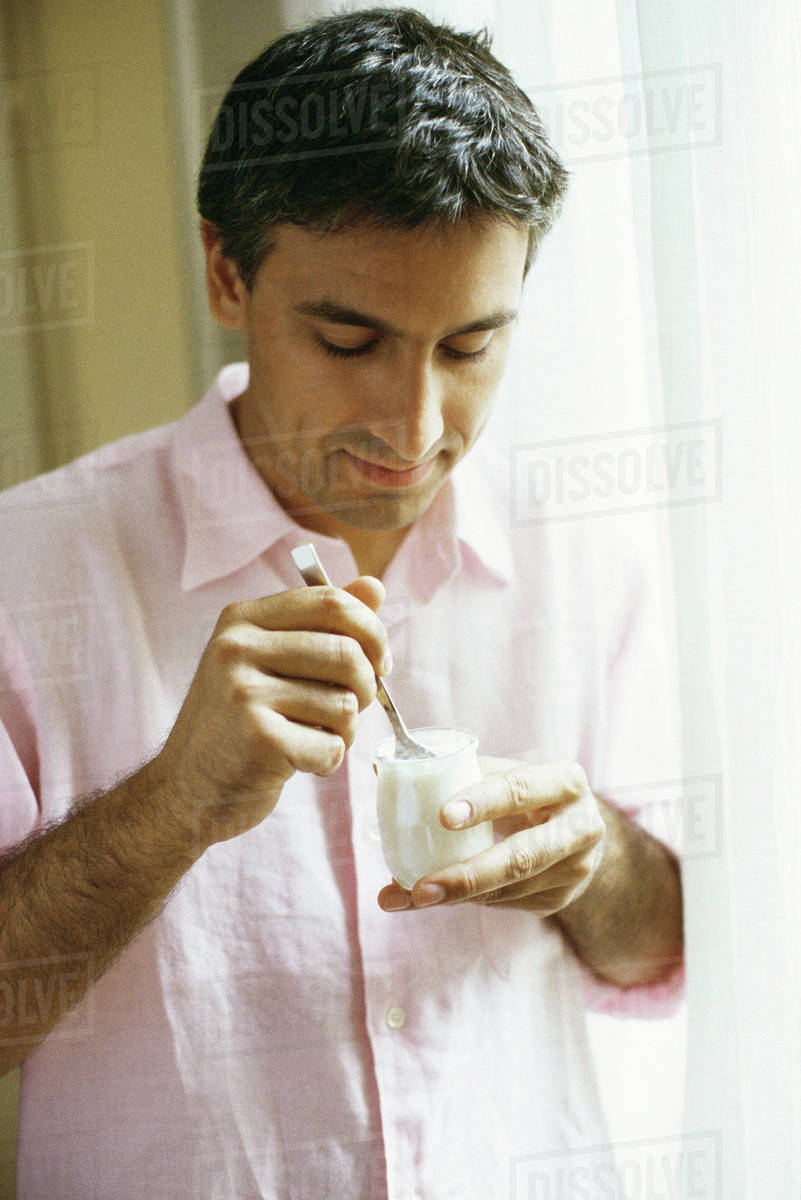 Man eating yogurt Stock Photo Dissolve