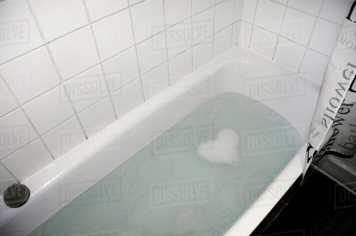 Soap suds forming heart shape in bathtub Stock Photo Dissolve