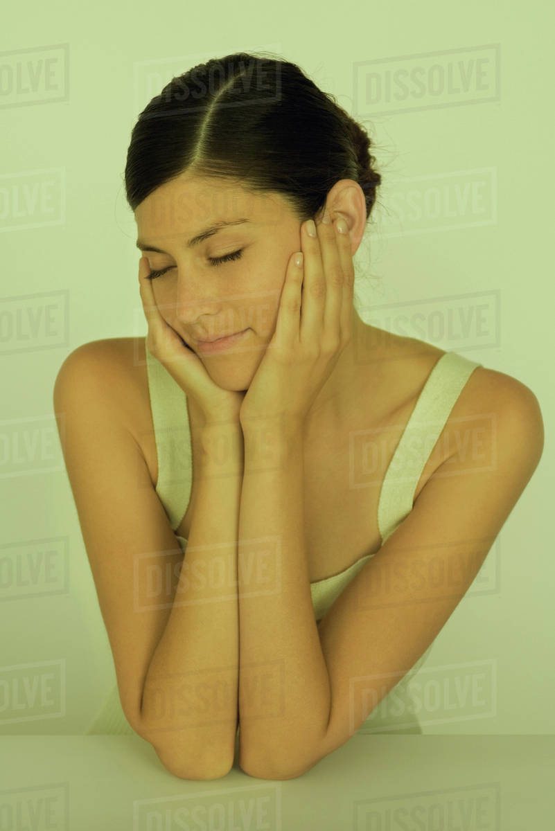 Young woman resting chin in hands, eyes closed, portrait Stock Photo Dissolve