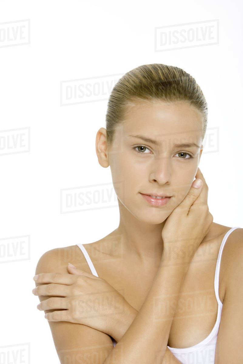 Young woman touching neck and shoulder, smiling at camera Stock Photo