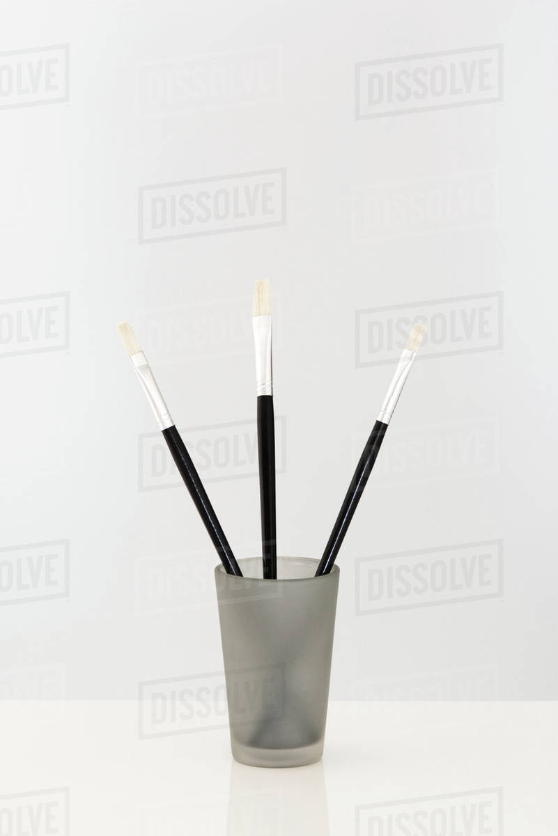 Paint brushes sticking out of cup, closeup Stock Photo Dissolve