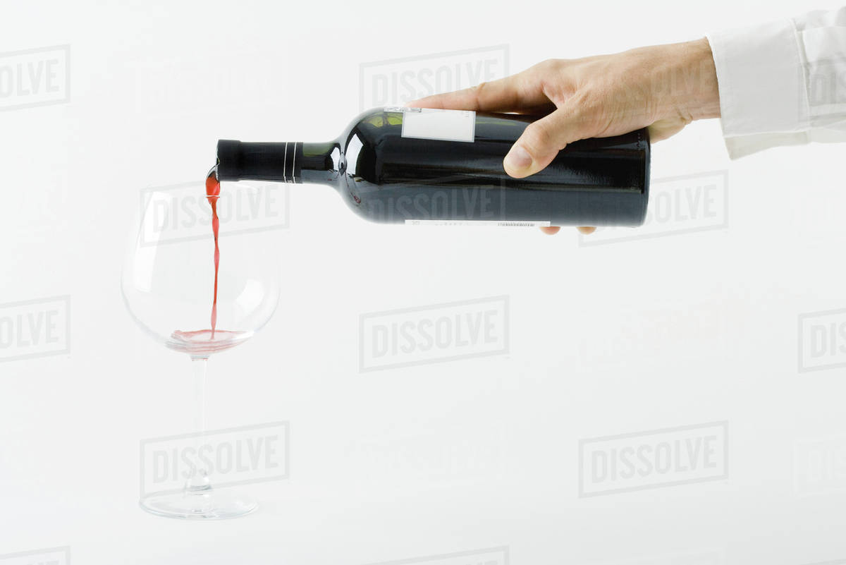 Man pouring red wine from bottle, cropped view of hand Stock Photo