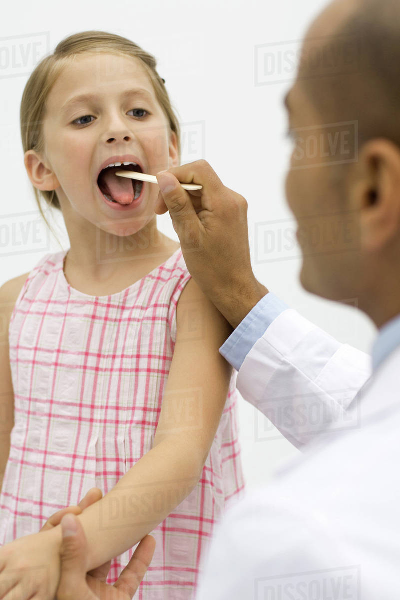 Doctor examining a girl's throat using a tongue depressor Stock Photo