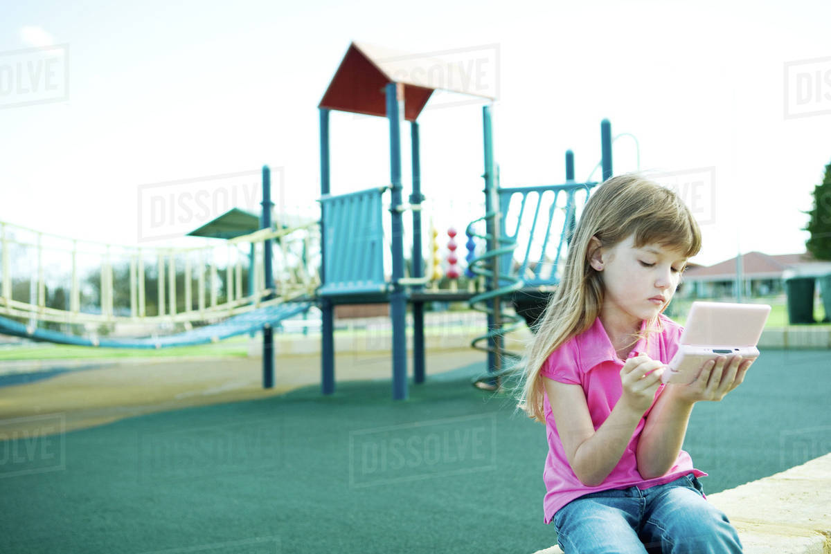Child on playground, playing video game Stock Photo Dissolve