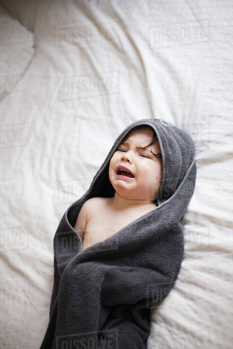 Crying toddler wrapped in a towel after bath Stock Photo Dissolve