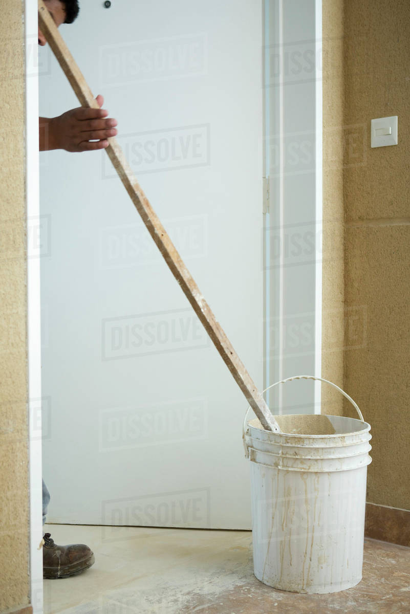 Worker mixing bucket of plaster Stock Photo Dissolve