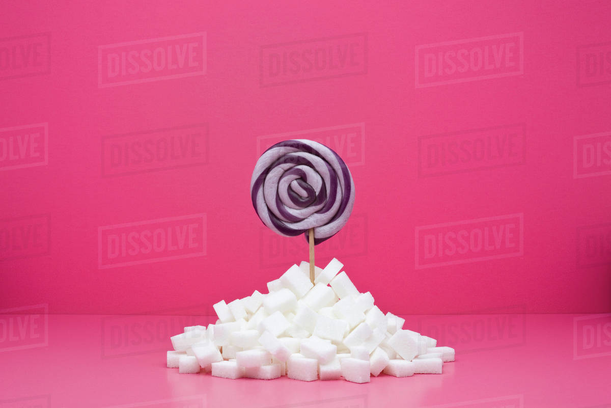Food Concept Lollipop Sticking Out From Pile Of Sugar Cubes
