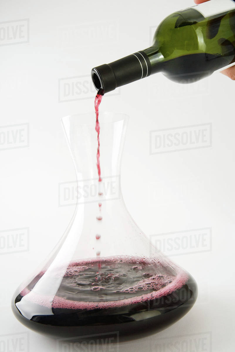 Pouring red wine into decanter, closeup Stock Photo Dissolve