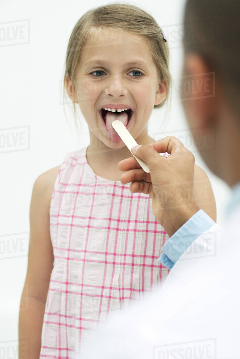 Doctor examining a girl's throat using a tongue depressor Stock Photo