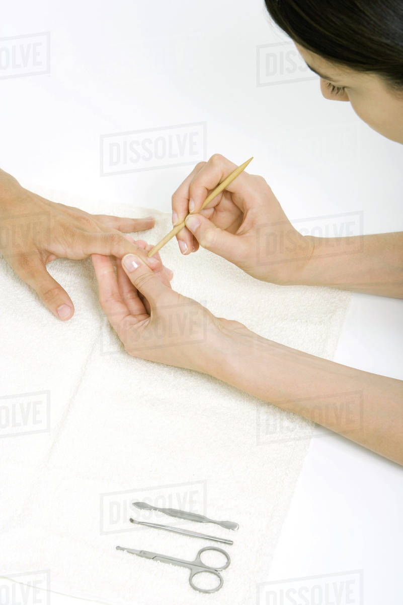 Woman using a cuticle pusher to give a manicure Stock Photo Dissolve