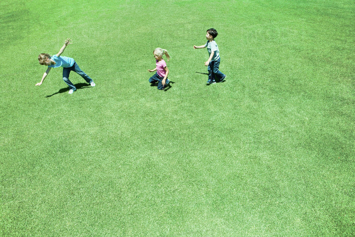 Children playing on grass, high angle view Stock Photo Dissolve