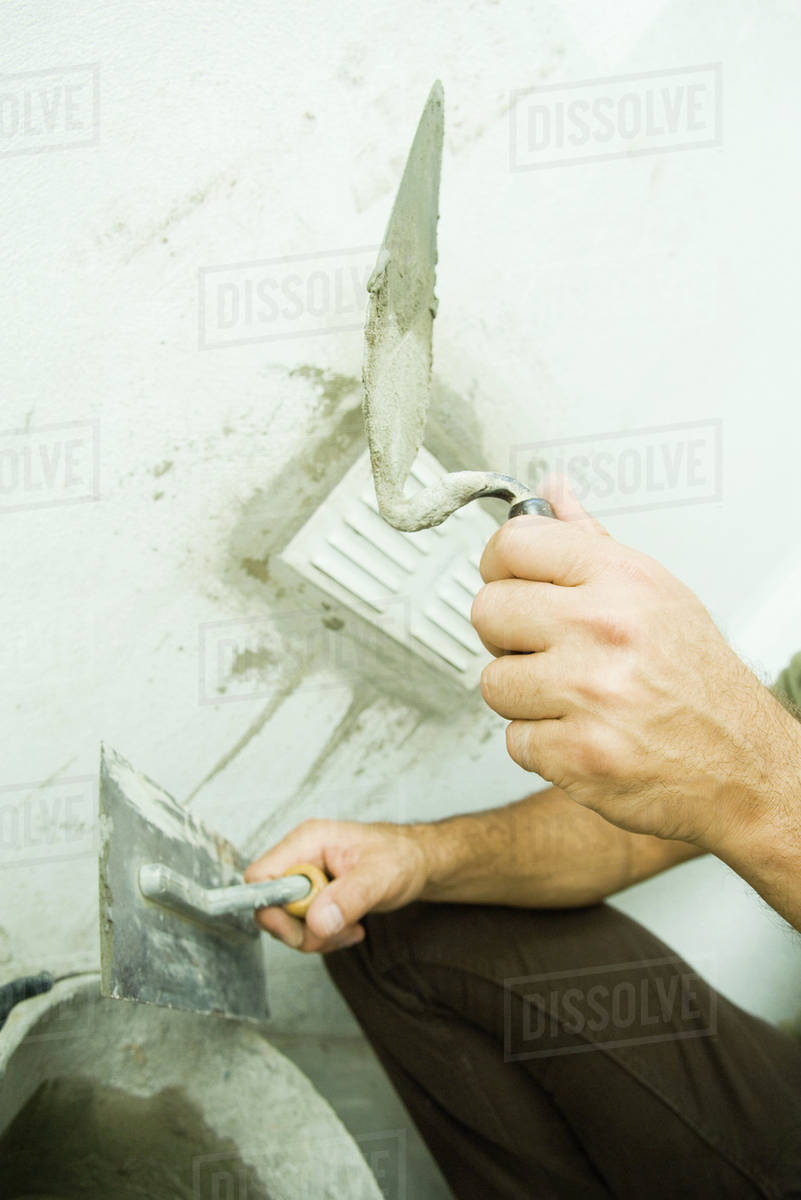 Man holding putty knife, cropped view Stock Photo Dissolve