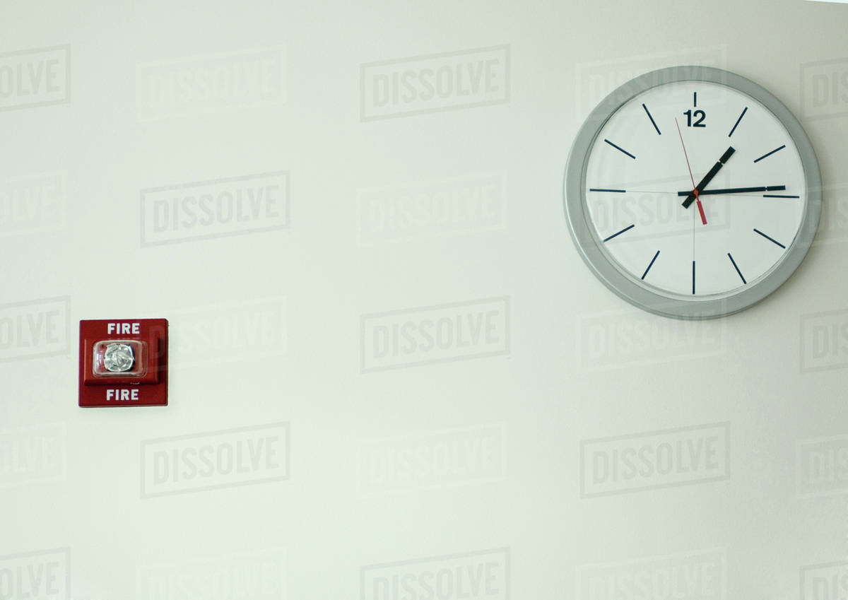 Clock and fire alarm on wall Stock Photo Dissolve
