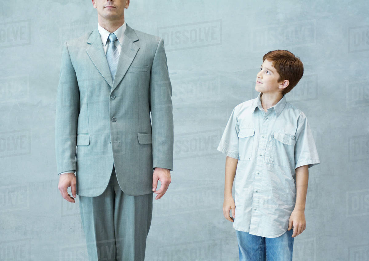 Boy looking up admiringly at businessman Stock Photo Dissolve