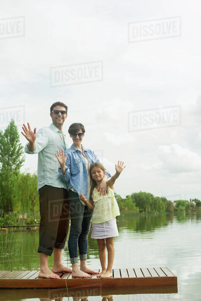 Family standing on dock waving Stock Photo Dissolve