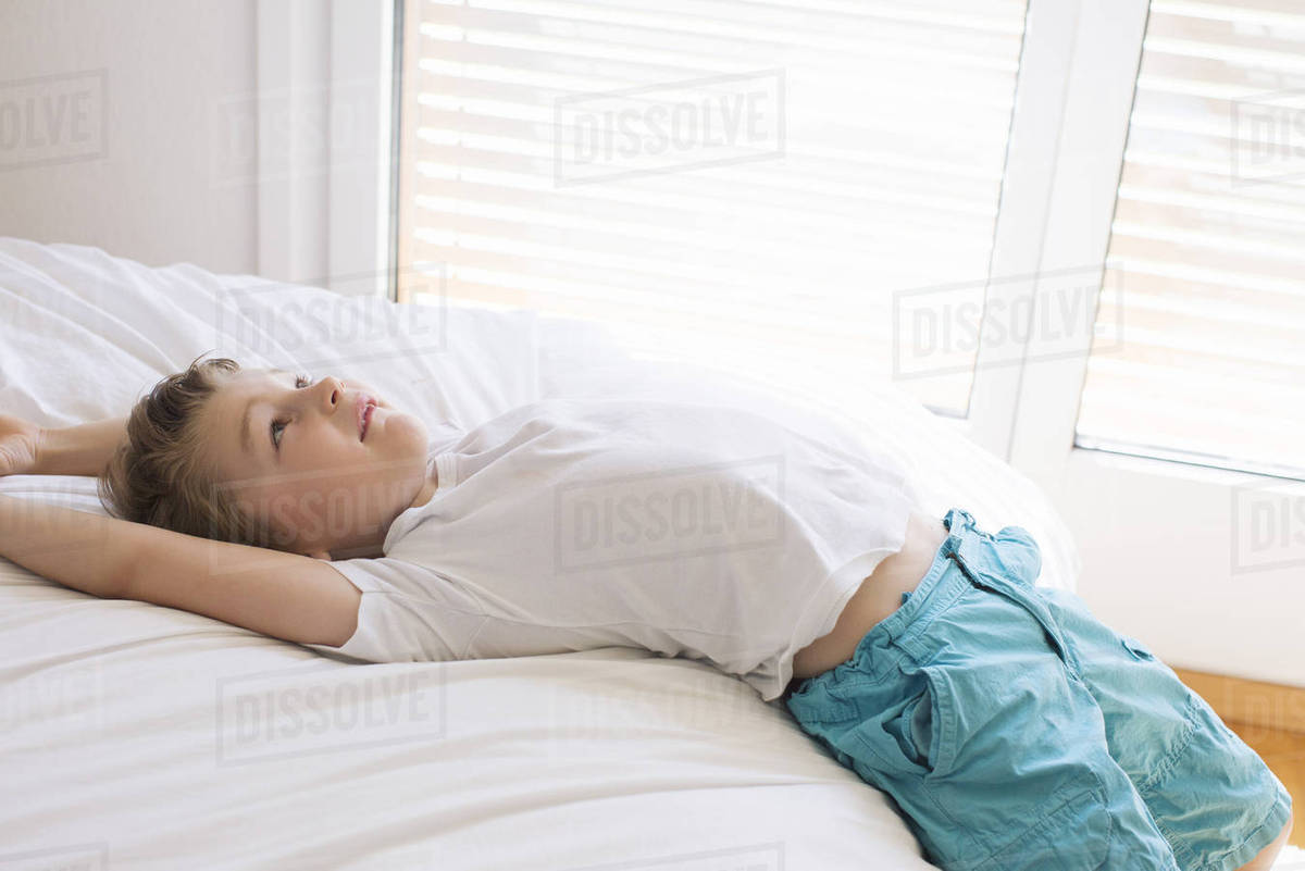 Boy relaxing on bed Stock Photo Dissolve