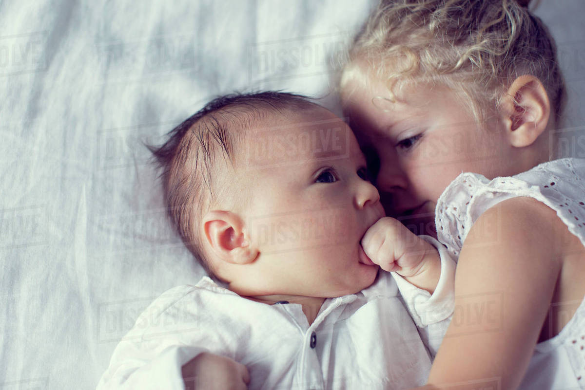 Little girl cuddling with baby brother Stock Photo Dissolve