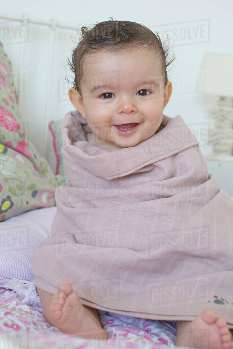 Baby wrapped in a towel, smiling, portrait Stock Photo Dissolve