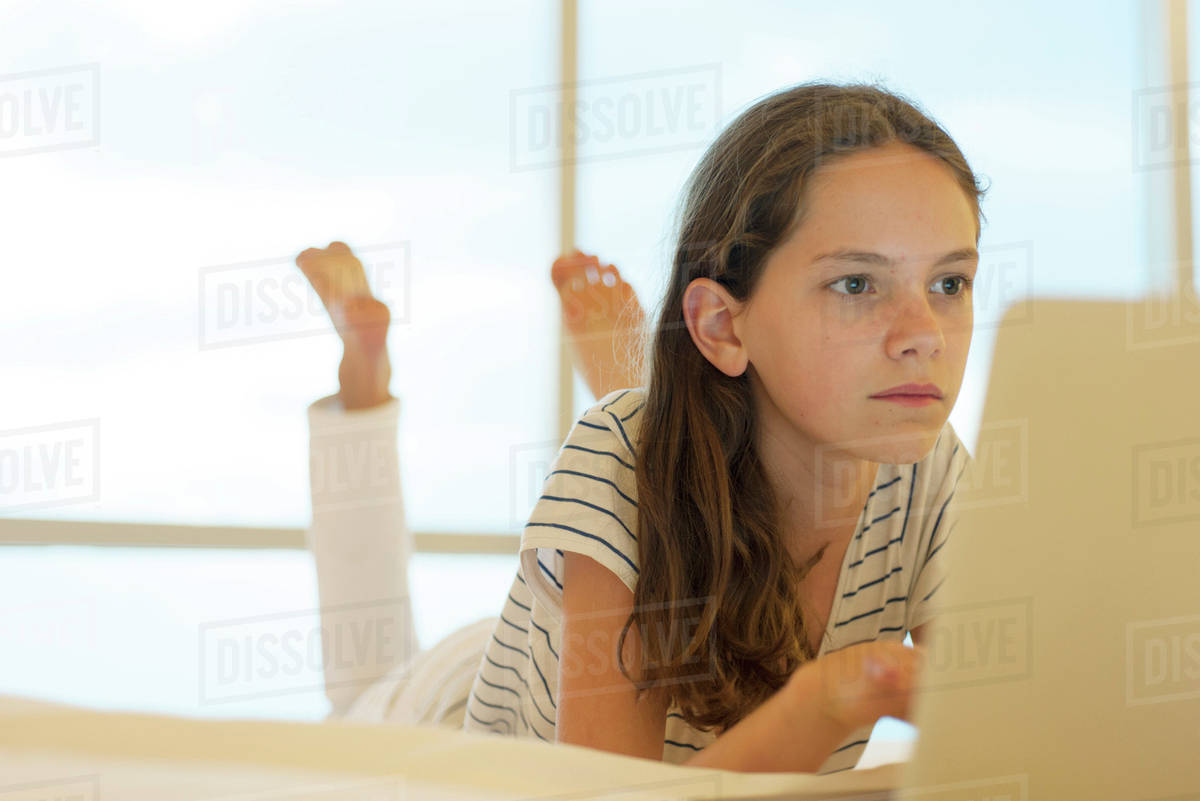 Preteen girl lying on stomach using laptop computer Stock Photo