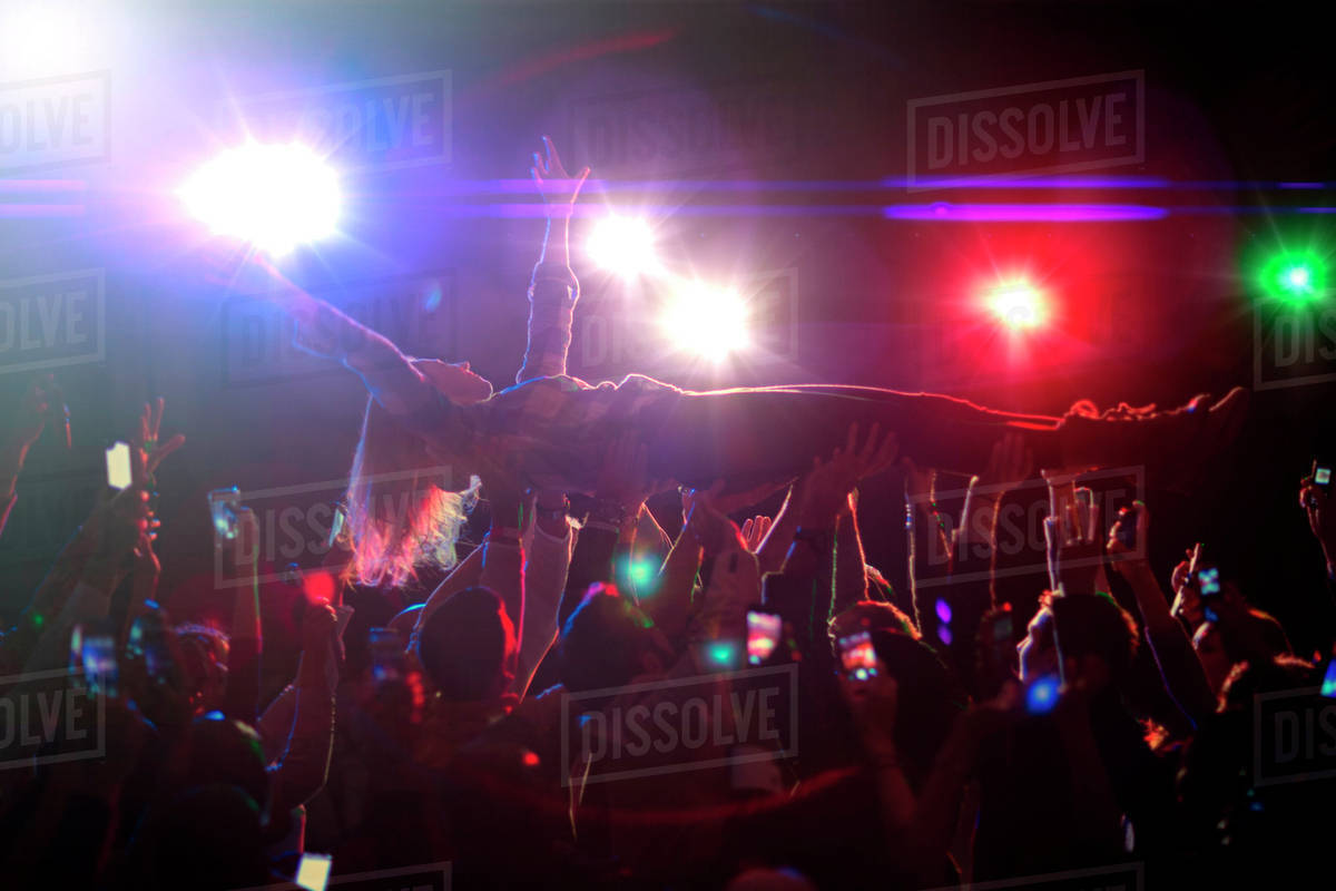 Woman crowd surfing at concert Stock Photo Dissolve