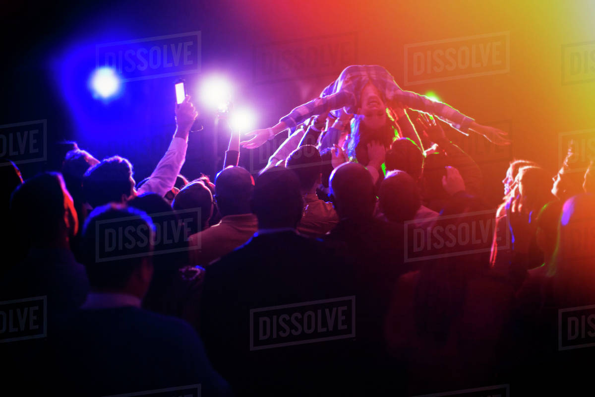 Woman crowd surfing at concert Stock Photo Dissolve
