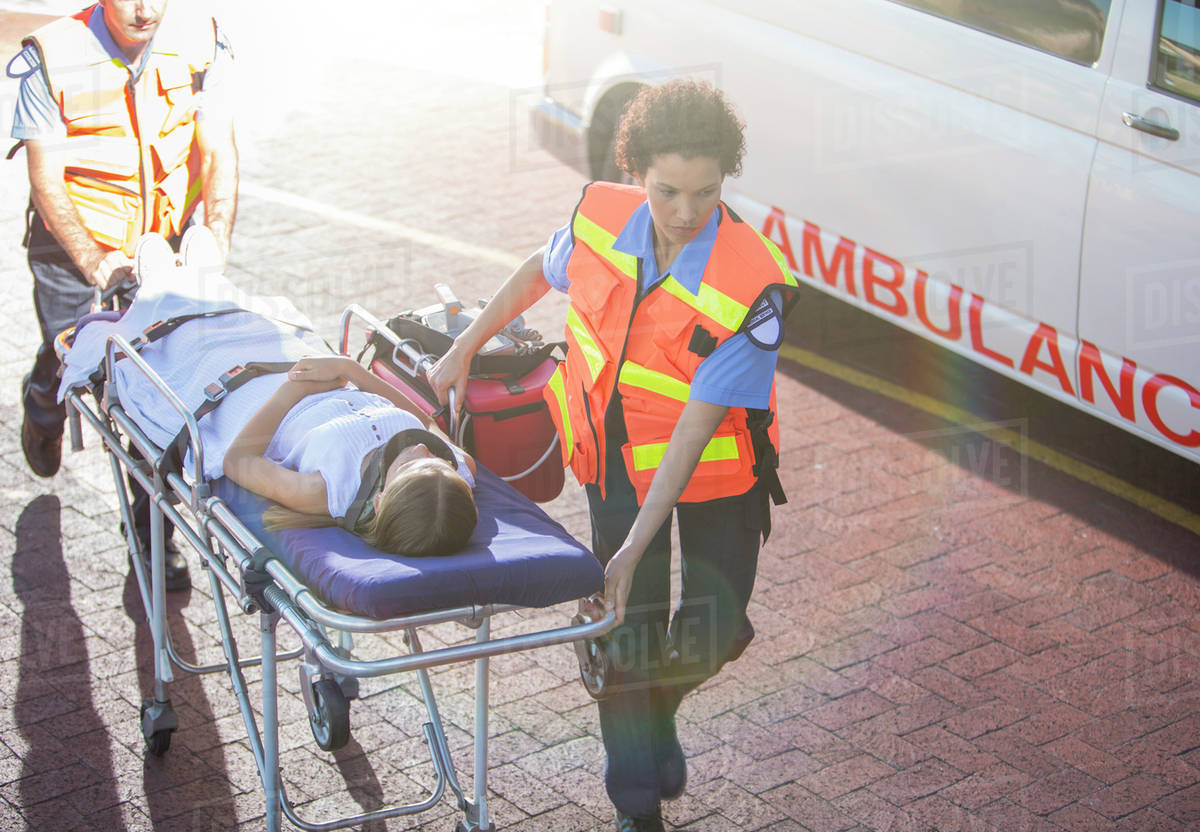 Paramedics wheeling patient in hospital parking lot Stock Photo