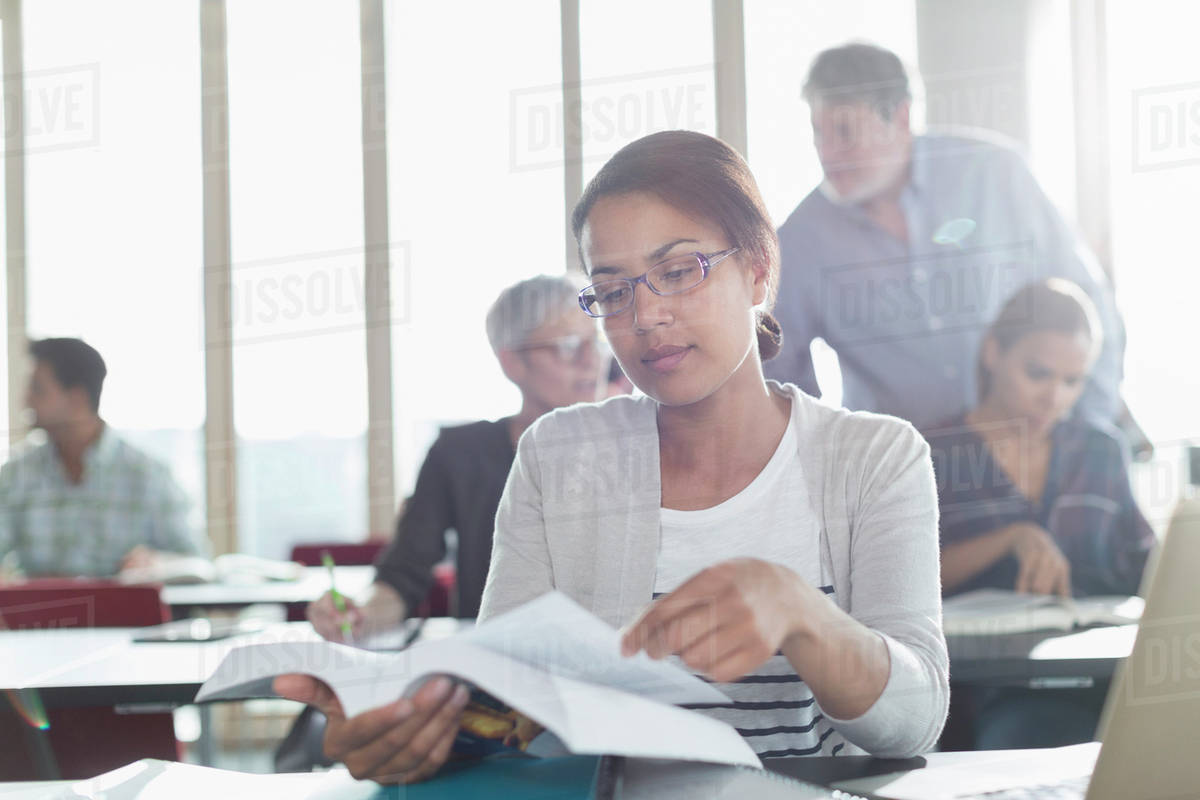 Student reading textbook in adult education classroom - Stock Photo