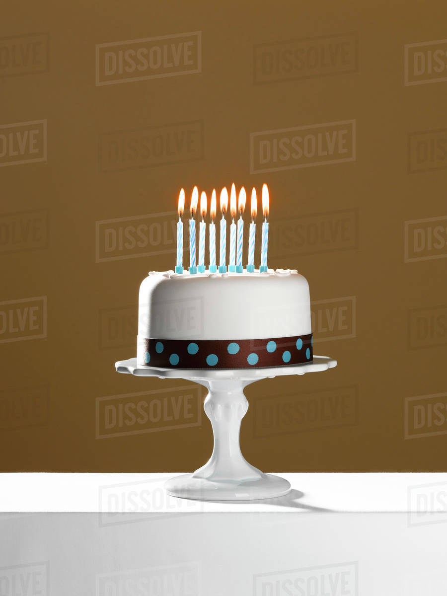 Birthday cake with lit candles on cake stand Stock Photo Dissolve