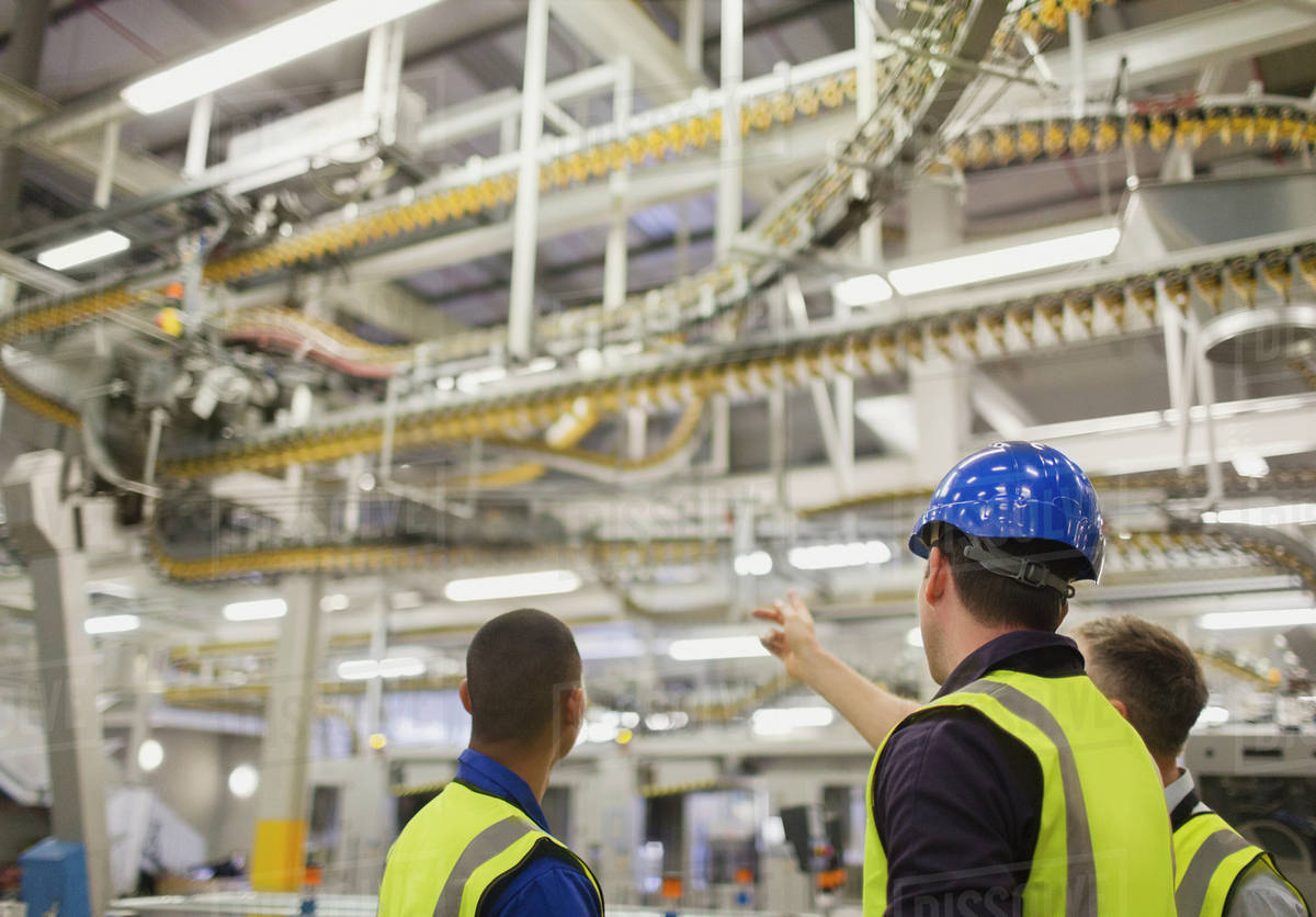 Workers discussing winding printing press conveyor belts overhead