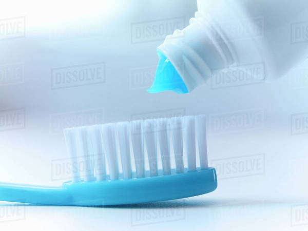Close-up of toothpaste squeezing on toothbrush - Stock Photo - Dissolve
