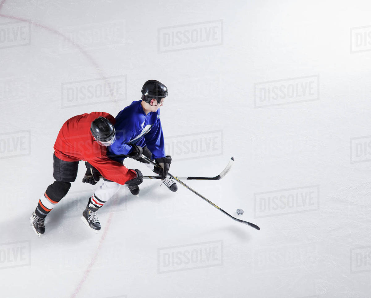 Hockey players going for puck on ice Stock Photo Dissolve