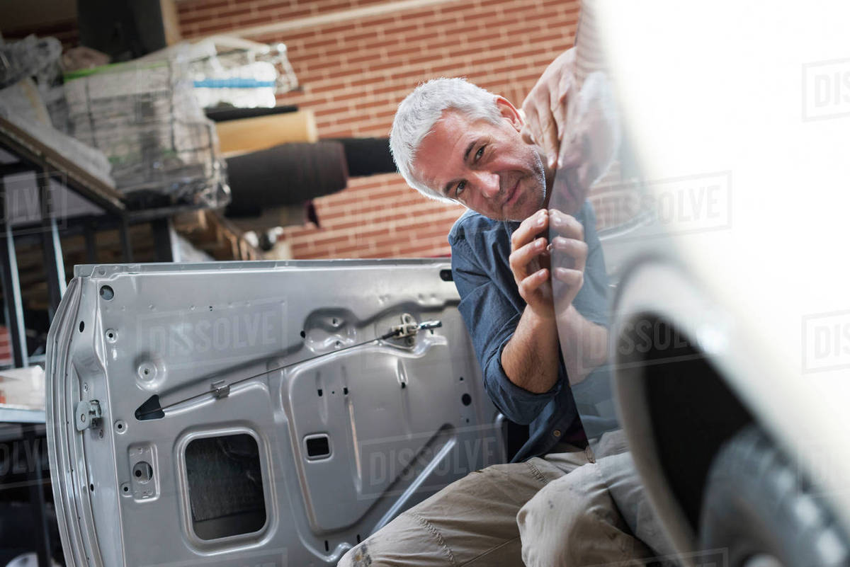 Focused auto body worker examining panel on car Stock Photo Dissolve